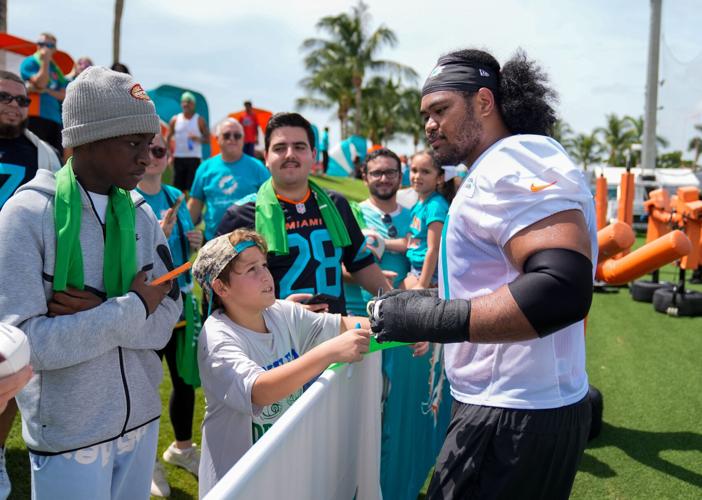 Miami Dolphins guard Jonah Savaiinaea (71) signs autographs for fans at training camp at Baptist Health Training Complex,