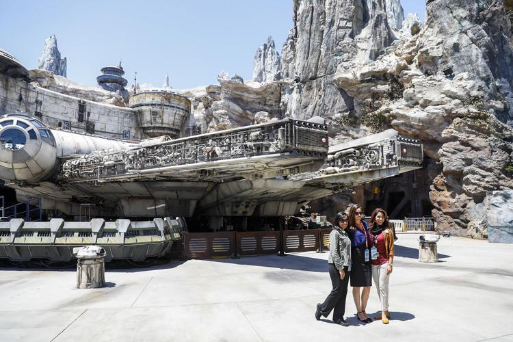 Disneyland Resort cast members pose for a photo in front of The Millennium Falcon: Smugglers Run ride, inside the new "Star Wars: Galaxy's Edge," at Disneyland Resort, in Anaheim, Calif, May 29, 2019.