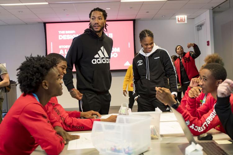 Derrick Rose works with students in a shoe design workshop.