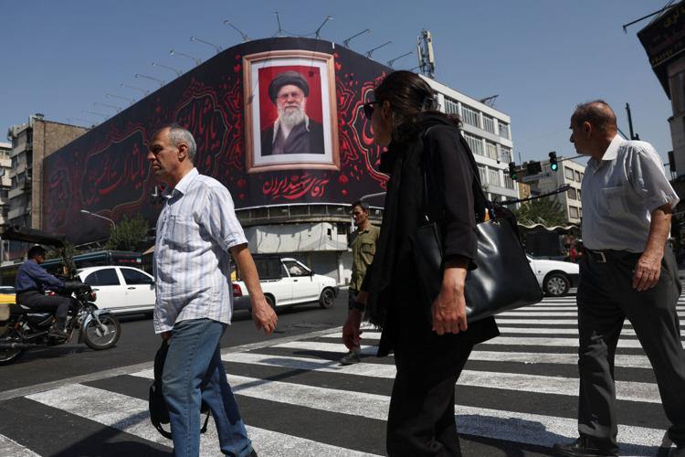 People walk past a billboard with an image of Iran's late Supreme Leader Ayatollah Ali Khamenei in Tehran