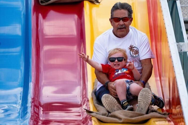 Jack Smith and grandson Aden Zahn, 2, ride the slide during Ankeny Summerfest on July 12, 2025, in Ankeny.