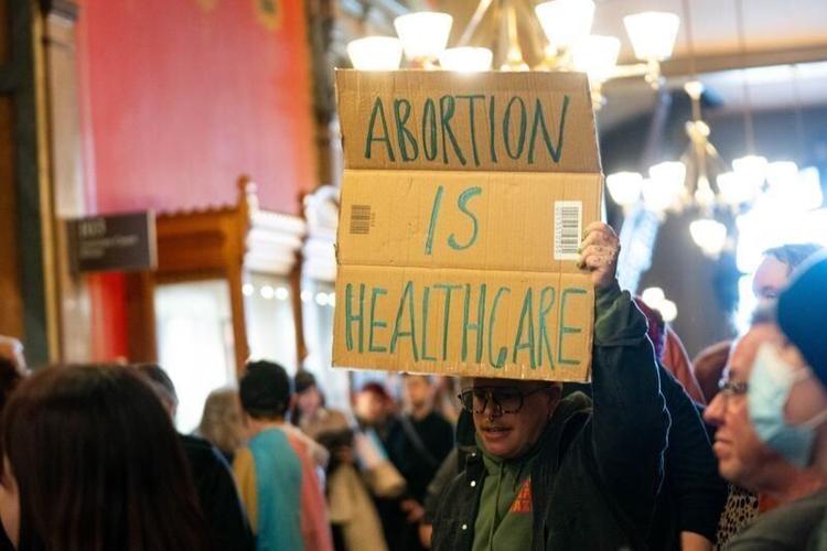 A protester holds a sign that reads "abortion is healthcare" as abortion abolitionists rally at the Iowa State Capitol on Feb. 9, 2026.