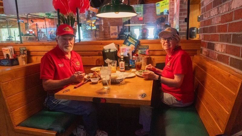 Mike and Judy McNamara smile at the camera with their food on the table June 24 at the Texas Roadhouse in West Des Moines.