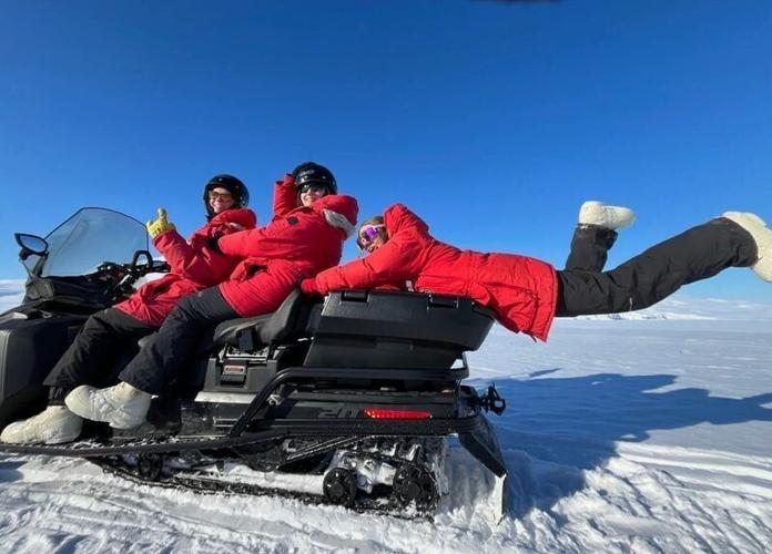A photo of the RAGBRAI tandem of Alayna Gibson, Holland Gillis and Sylvia Torkelson on a snowmobile in Antarctica in spring 2026.