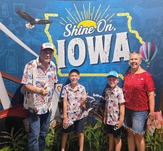 Gary Leffler and his family stand in front of the Iowa sign at the Great American State Fair.