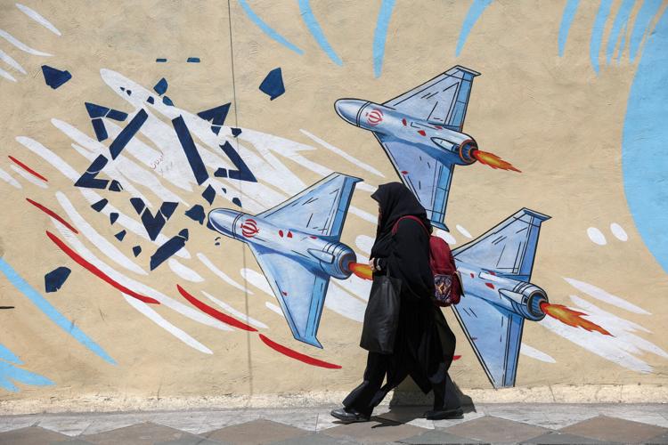 An Iranian woman walks past an anti-Israeli mural in Tehran