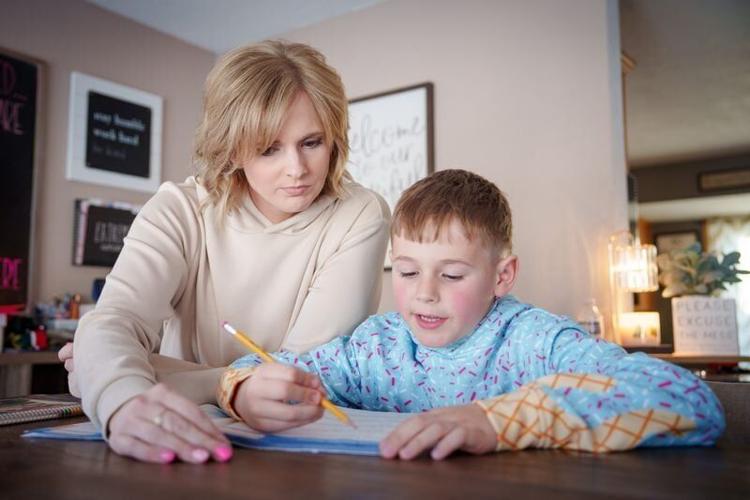 Megan Rassel looks over a workbook with her son Kolten Gehling, 8, at their home in Carroll, Feb. 20, 2026.