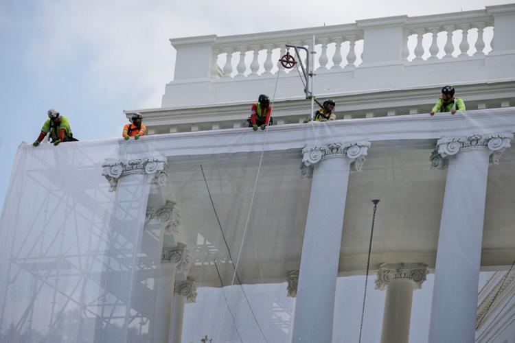 Workers install a tarp as they do maintenance on the stone of the North Portico of the White House