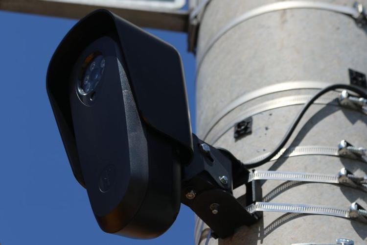 This Flock camera, at the intersection of Broadway and Exchange Street in Pawtucket, Rhode Island, is mounted on a metal utility pole, nestled amid street signs and crosswalk signals.