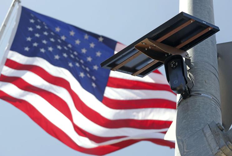An American flag flies behind a Flock Safety camera mounted to a light pole on Aug. 3, 2026, in Burbank, Calif.