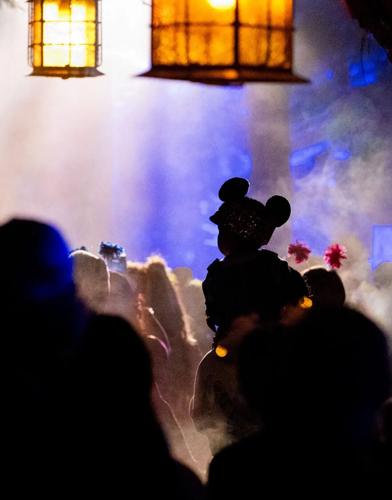 A young attendee adorns Mickey Mouse ears while making their way through Villains Grove during Oogie Boogie Bash at Disney California Adventure Park.