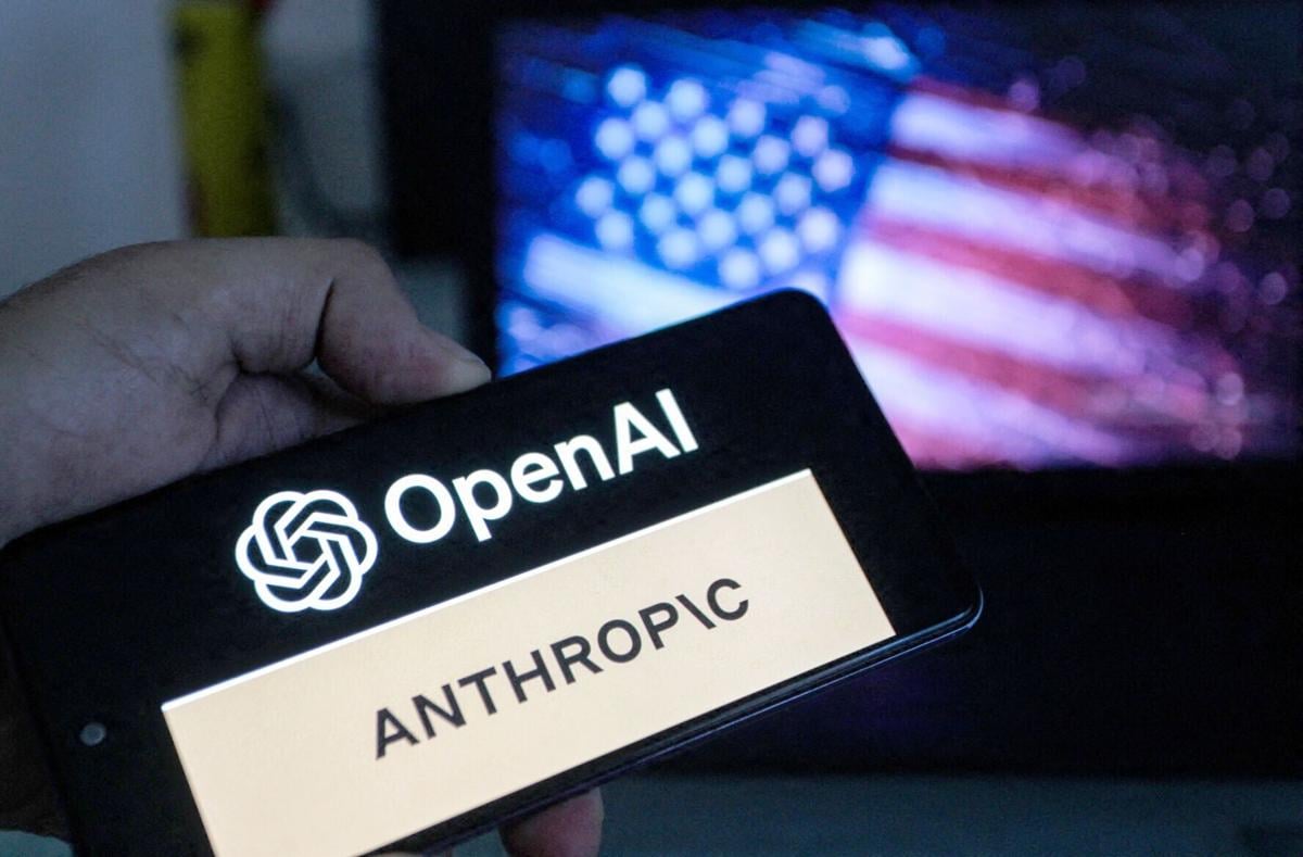 A smartphone screen displays the logos of OpenAI and Anthropic against a blurred backdrop of the American flag, symbolizing the intensifying competition in artificial intelligence between the two US-based companies in Tunis, Tunisia on June 17,2026.