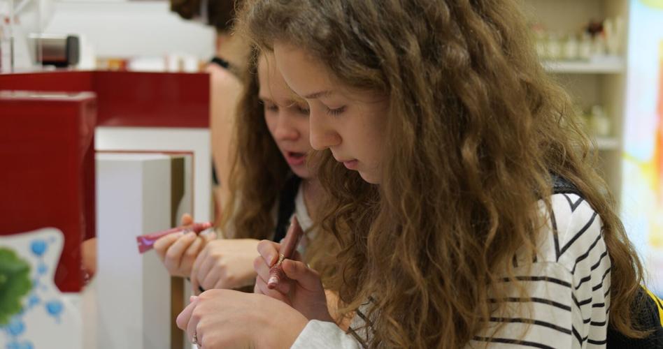 Women test lipstick colors by making small swatches on hands in cosmetics store