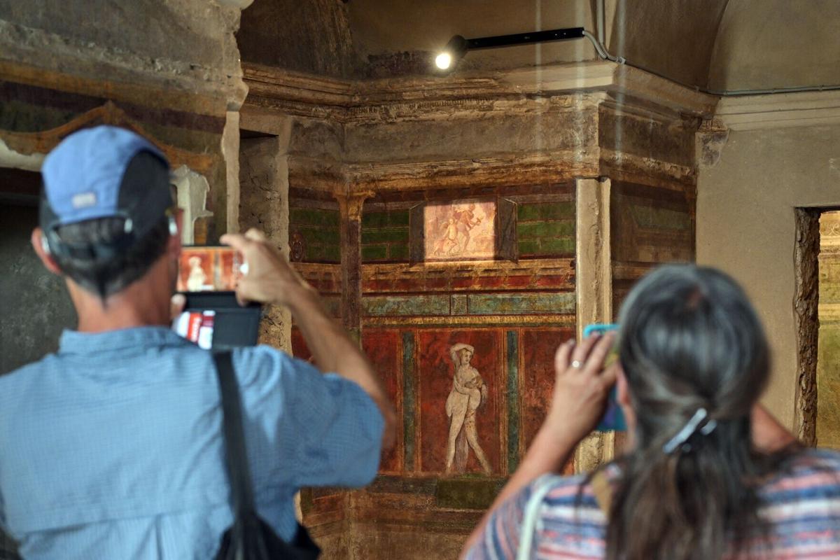 Tourists take pictures in the' Villa of Mysteries' lit by green energy as the roof has been partly retiled with solar panels, on April 15, 2024 in Pompeii. The photovoltaic tiles look just like the ancient tiles of Pompeii but have solar cells inside, a...