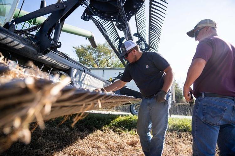 Kevin and Steve Kuiper troubleshoot a loose bolt on the combine used to harvest soybeans on Wednesday, Oct. 2, 2024, near Bussey.