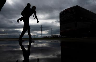 A man carries a child on his back as he walks to board a bus for evacuation before the arrival of hurricane Laura in Lake Charles, Louisiana on August 25, 2020 amid the coronavirus pandemic.