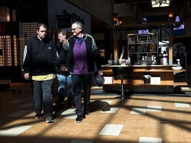 Sam Walker (left) walks hand-in-hand with his father Kent (right) during a trip to Jordan Creek Town Center on Feb. 26, 2026, in West Des Moines. The family is calling for the state’s Medicaid program to continue their adult son Sam’s care after they we...
