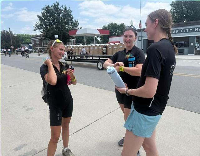 Sylvia Torkelson, Holland Gillis and Alayna Gibson laugh while waiting in line at a food vendor in Dunlap, Iowa, on July 19, 2026.