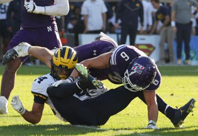 Northwestern safety Robert Fitzgerald tackles Michigan running back Bryson Kuzdzal in the fourth quarter Nov. 15, 2025, at Wrigley Field in Chicago.