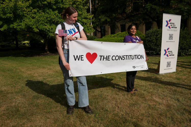 Ohio League of Women Voters members Ava Brady, left, and Munia Mostafa hold a sign during the Justice In Motion bus tour stop in Columbus, Ohio on July 8, 2026.