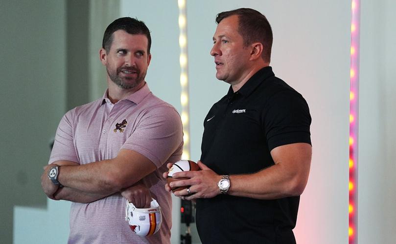 Iowa State football coach Jimmy Rogers and men’s basketball head coach T.J. Otzelberger talks to each other during Cyclone