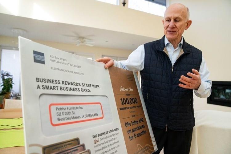 West Des Moines resident John Duesing holds a large poster of mail sent to his home address on Monday, Feb. 10, 2025. Duesing and his Hickory Ridge Estates neighbors noticed someone registered a furniture business at their home addresses last summer.