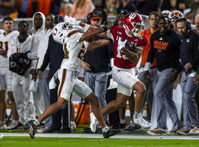 Indiana wide receiver Elijah Sarratt pushes away University of Miami defensive back Ethan O'Connor after a catch and run along the sidelines during the first half of the College Football Playoff national championship game at the Hard Rock Stadium on Mon...
