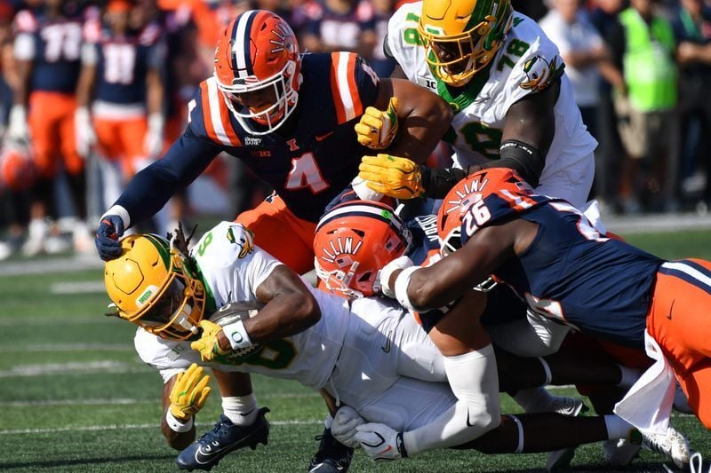 Oregon  running back Dierre Hill Jr., left, is brought down by the Illinois defense during the first half at Gies Memorial Stadium in Champaign, Illinois on Oct. 24, 2026.
