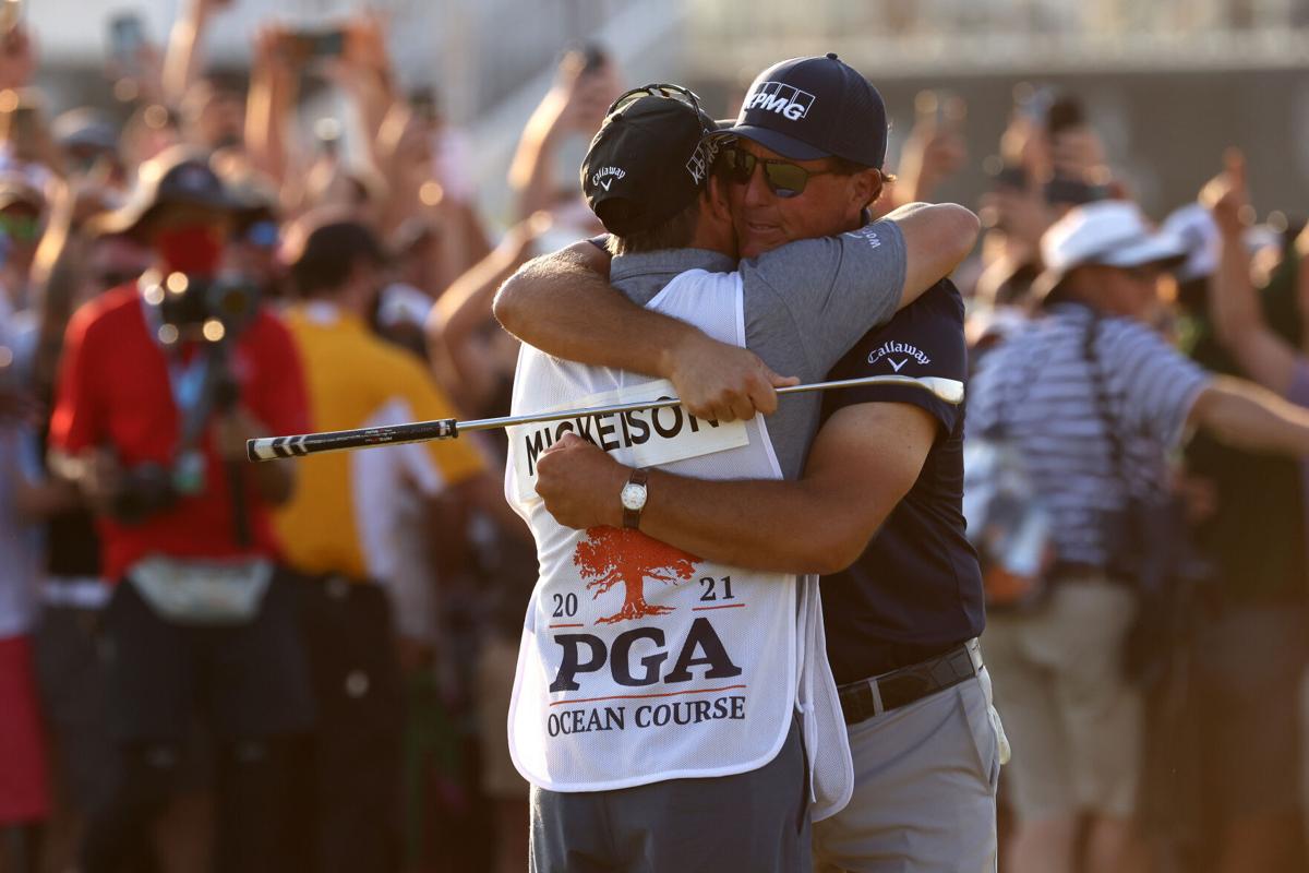 Phil Mickelson of the United States celebrates with brother and caddie Tim Mickelson on the 18th green after winning during the final round of the 2021 PGA Championship held at the Ocean Course of Kiawah Island Golf Resort on May 23, 2021 in Kiawah Isla...