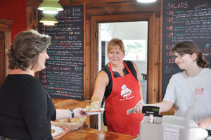 Susan Grant, in the apron, delivers lunch to a customer at the Apple Core Luncheonette, now open seven days a week at Cold Hollow Cider Mill in Waterbury Center.