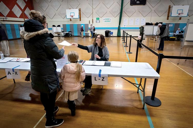Cyndi Freeman hands a ballot to a voter