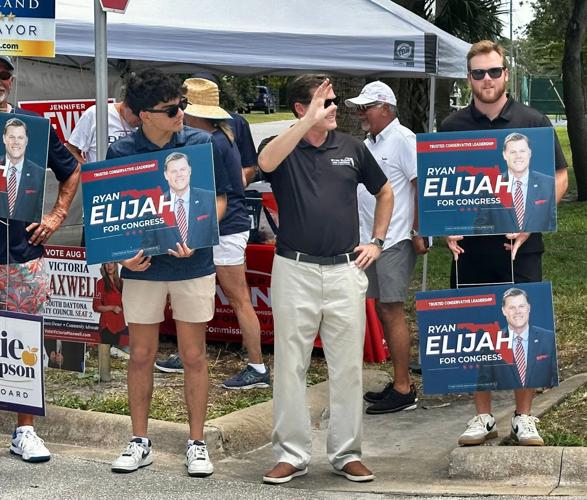 Congressional candidate Ryan Elijah, center, waves to voters at the New Smyrna Beach Regional Library during the Florida primary