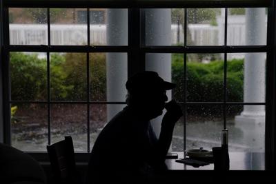 A man drinks coffee in a hotel lobby that has lost its power as Hurricane Florence comes ashore on Wilmington