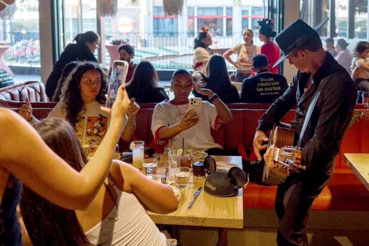 Content creators record a Spanish guitar performer during a Disney influencer event in Downtown Disney District.