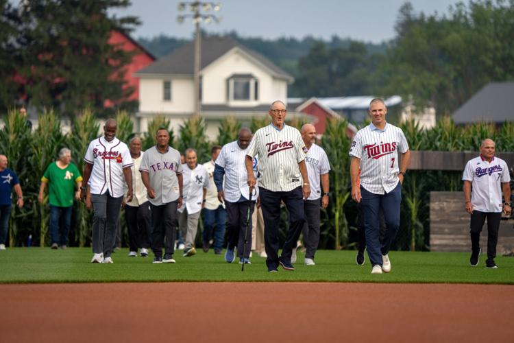Members of the Baseball Hall of Fame walk out of the corn before a game between the Philadelphia Phillies and the Minnesota