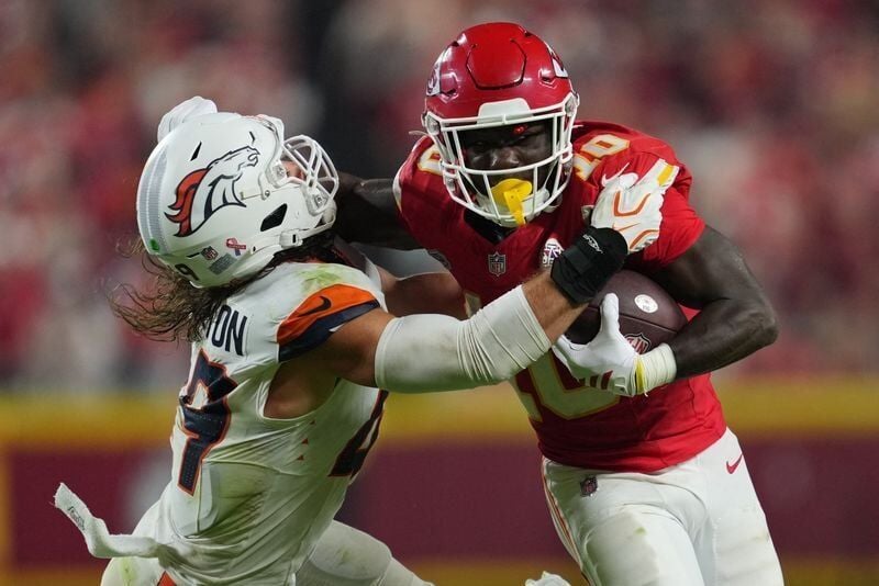 Sep 14, 2026; Kansas City, Missouri, USA;  Kansas City Chiefs running back Emmett Johnson (10) rushes the ball against Denver Broncos linebacker Alex Singleton (49) at GEHA Field at Arrowhead Stadium.  Mandatory Credit: Jay Biggerstaff-Imagn Images