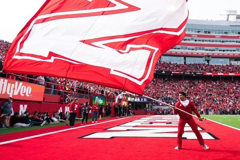 Oct 25, 2025; Lincoln, Nebraska, USA; A Nebraska Cornhuskers cheerleader waves a school flag after a touchdown against the Northwestern Wildcats during the fourth quarter at Memorial Stadium. Mandatory Credit: Dylan Widger-Imagn Images