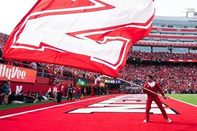 Oct 25, 2025; Lincoln, Nebraska, USA; A Nebraska Cornhuskers cheerleader waves a school flag after a touchdown against the Northwestern Wildcats during the fourth quarter at Memorial Stadium. Mandatory Credit: Dylan Widger-Imagn Images