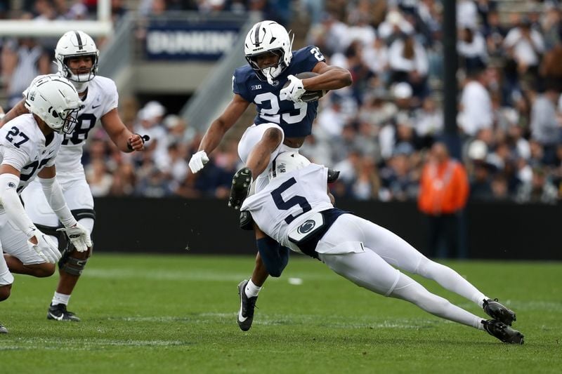 Apr 26, 2025; University Park, PA, USA; Penn State Nittany Lions running back Tikey Hayes (23) leaps over cornerback Daryus Dixson (5) during the third quarter of the Blue White spring game at Beaver Stadium. The White team defeated the Blue team 10-8. ...