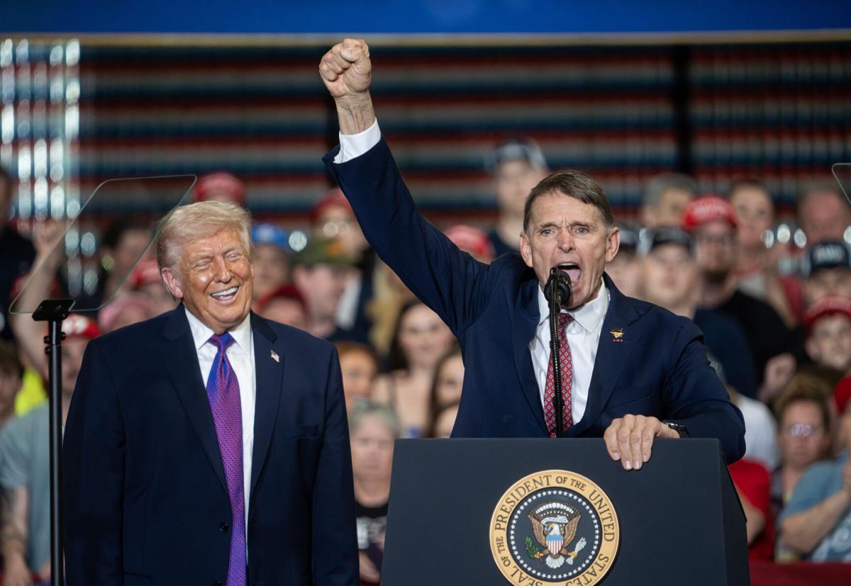 Former Navy SEAL officer Ed Gallrein speaks as President Donald Trump smiles while looking on during a visit to Verst Logistics on March 11, 2026, in Hebron, Ky. Trump is backing Gallrein in a challenge to Rep. Thomas Massie, R-Ky., in the November 2026 mi