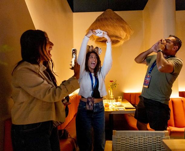Content creator Angela Aguilar reacts and holds up a sticker that wins her and her family a trip on a Disney cruise during a Disney influencer event in Downtown Disney District.