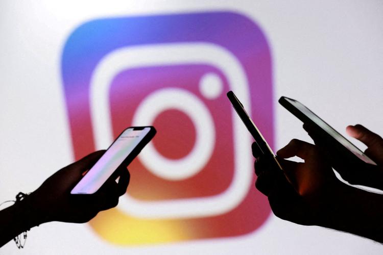 FILE PHOTO: Illustration shows teenagers pose for a photo while holding smartphones in front of a Instagram logo