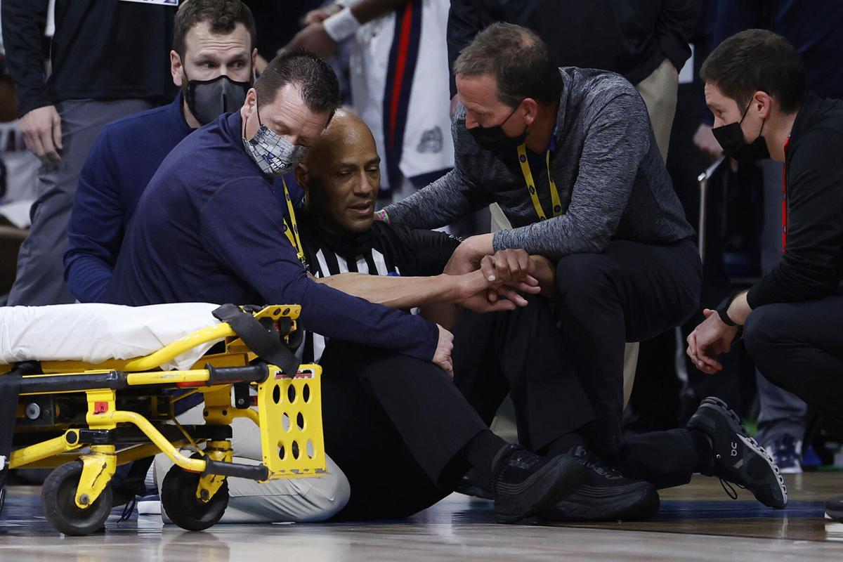 Referee Bert Smith is tended to by training staff and medical personnel after collapsing during the first half of the Elite Eight round game between the USC Trojans and the Gonzaga Bulldogs during the 2021 NCAA Men's Basketball Tournament at Lucas Oil S...