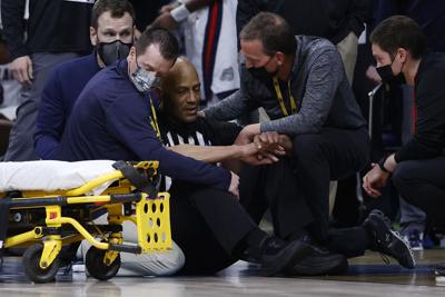 Referee Bert Smith is tended to by training staff and medical personnel after collapsing during the first half of the Elite Eight round game between the USC Trojans and the Gonzaga Bulldogs during the 2021 NCAA Men's Basketball Tournament at Lucas Oil S...