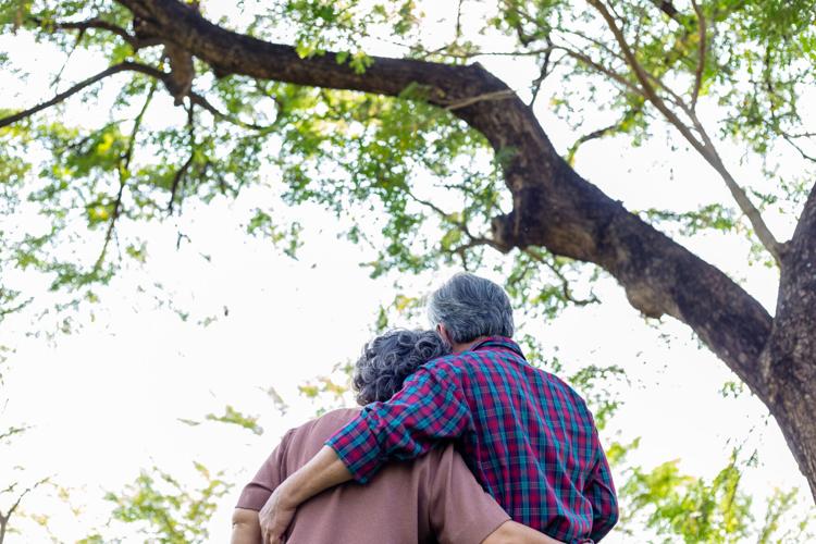 Happy old asian couple under tree Old man and Old woman or Grandfather and grandmother embracing each other with love Elderly husband hug old wife and spending time together with happiness Health care