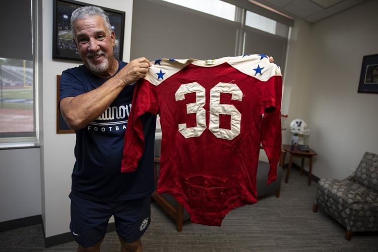 Mark Ferrante holds up an all-star jersey worn by former Villanova fullback Ralph Pasquariello, who played on the 1950 college team that defeated the Eagles in the Chicago Charities College All-Star Game.