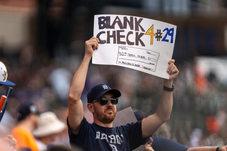 A Detroit Tigers fan holds a handmade sign offering a blank check to Tigers pitcher Tarik Skubal (29) during a game against the