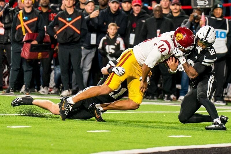 Nov 1, 2025; Lincoln, Nebraska, USA; Southern California Trojans quarterback Jayden Maiava (14) is tackled by Nebraska Cornhuskers defensive back Rex Guthrie (21) and defensive back Andrew Marshall (10) during the second quarter at Memorial Stadium. Man...