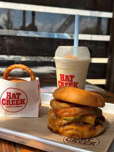 Hat Creek Burger Company's Pitmaster Stack, a limited-time burger layered with chopped brisket from Terry Black’s Barbecue, BBQ sauce, melted cheddar, pickles and crispy onion rings.