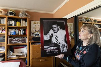 Melanie Jackson, daughter of iconic college football broadcaster Keith Jackson, holds up a photo of the iconic broadcaster at his one-time home on Thursday, Jan. 1, 2026, in the Sherman Oaks neighborhood of Los Angeles.
